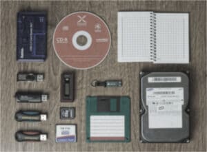 USB-Sticks, Festplatte, Diskette, CD, Speicherkarte und Notizbuch auf einem Holztisch
