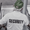 Ein Mann mit grüner Mütze und Security-Shirt auf einer Rolltreppe