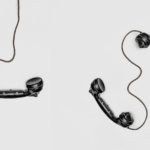 Drei schwarze Telefonhörer auf weißem Grund